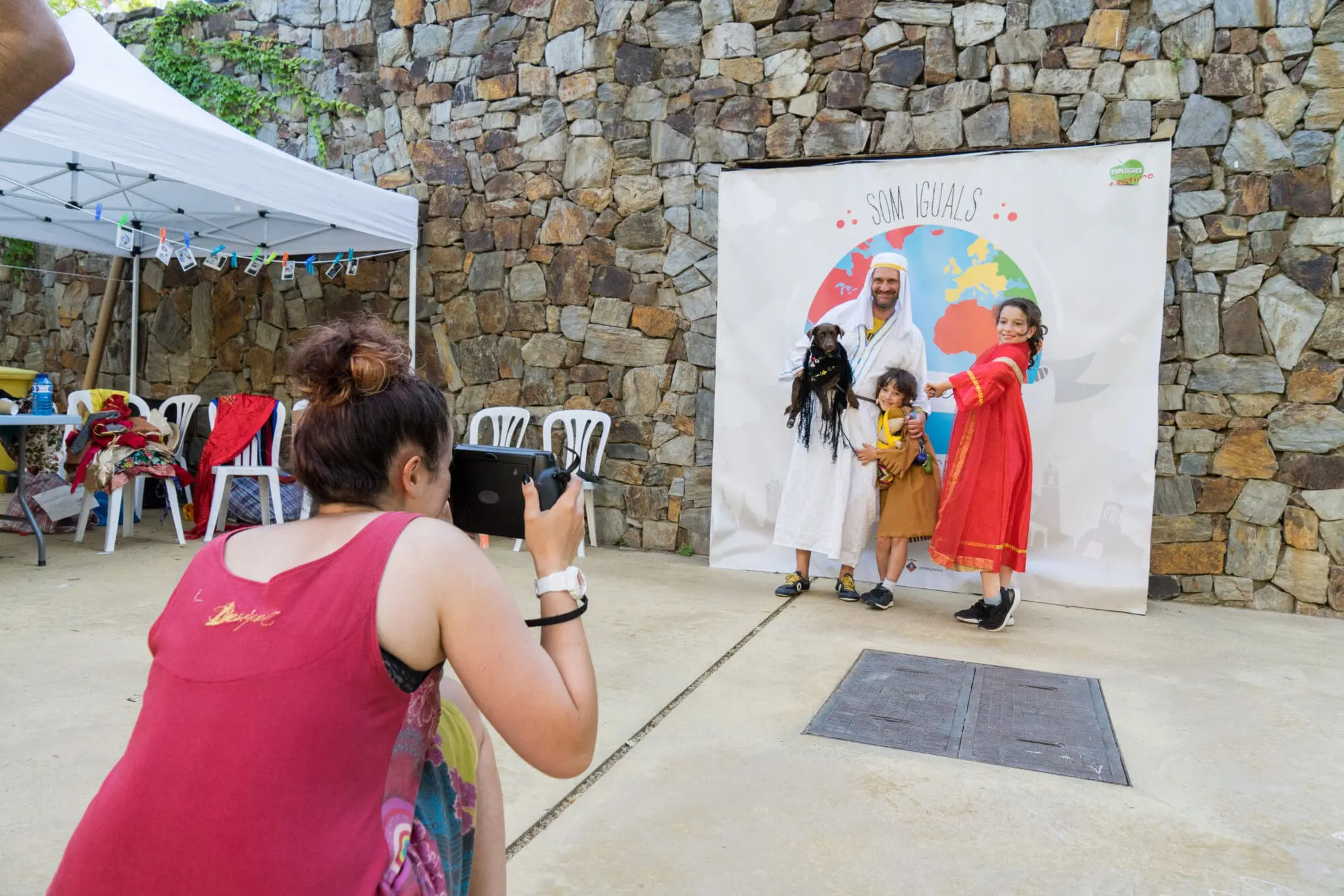 Noia que fa una foto a una família en el dia de la Festa del Joc