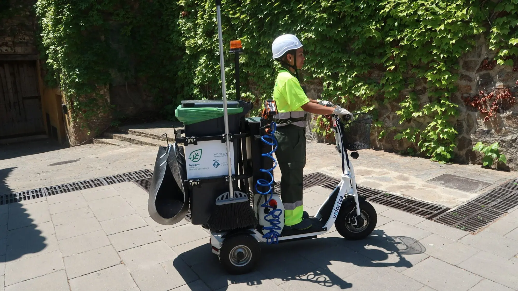 Una noia del servei de neteja condueix un vehicle de servei tricicle pel carrer