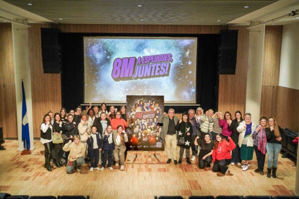 Participants de la campanya realitzant un gest de lluita i empoderament femení al costat del cartell de la campanya 'A Esplugues juntes'